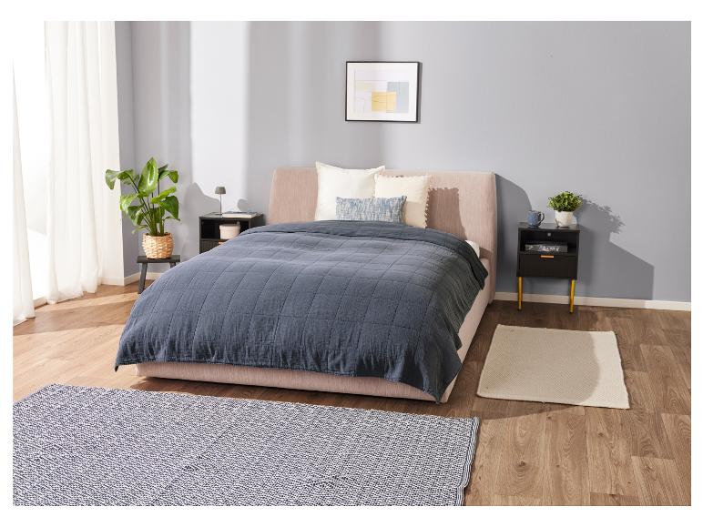 Lit, couvre-lit bleu marine et tables de chevet dans une chambre moderne.