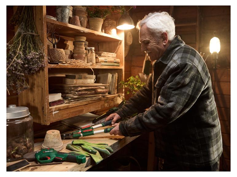 Un homme âgé utilise des outils de jardinage Parkside dans son atelier rustique.