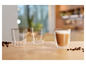 Trois verres de cappuccino et des grains de café sur une table en bois.
