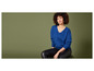Une femme porte un pull bleu et un pantalon en cuir noir.