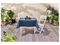 Une nappe bleue sur une table en bois avec des chaises blanches dans le jardin.