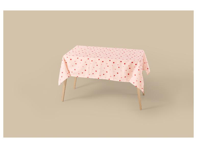 Nappe rose à motifs de fraises sur une table en bois.