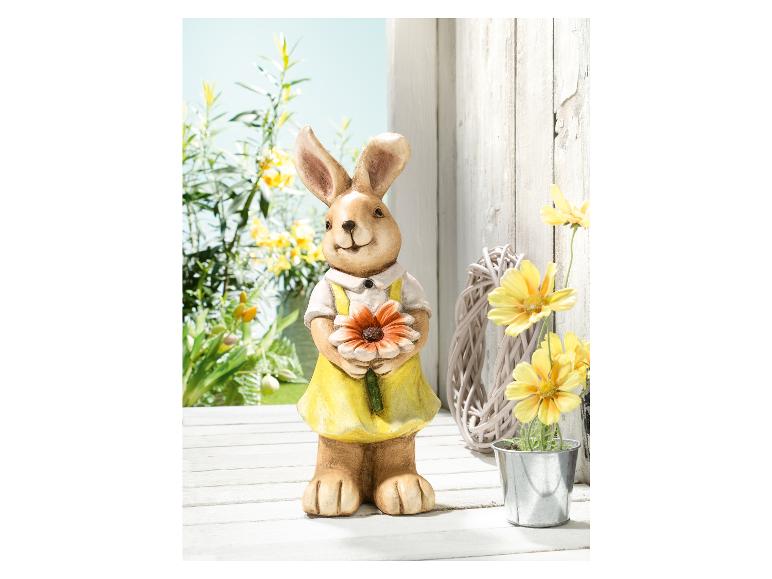 Un lapin de Pâques tenant une fleur, entouré de fleurs jaunes.