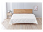 Une couette blanche à motif matelassé sur un cadre de lit en bois.