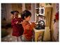 Deux enfants jouent dans une cuisine miniature avec un four et un évier.