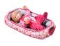 Poupée Baby Born en pyjama rose avec tétine, allongée dans un couffin doux et à motifs.