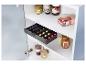 Un tiroir coulissant avec des capsules de café sous une armoire de cuisine.