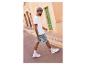 Un homme en t-shirt blanc, short en jean bleu et baskets blanches marche dans la rue.