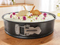 Un moule à gâteau avec un gâteau blanc décoré de fleurs violettes et de biscuits en forme de lapins