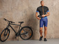 Un homme en tenue de vélo avec un casque et un vélo noir.