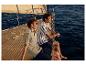 Deux hommes en polos et shorts décontractés sur un yacht.