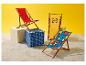 Trois chaises de plage aux motifs géométriques et une avec logo, sur le sable.