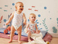 Deux bébés en tenues d'été mignonnes jouent sur un tapis.