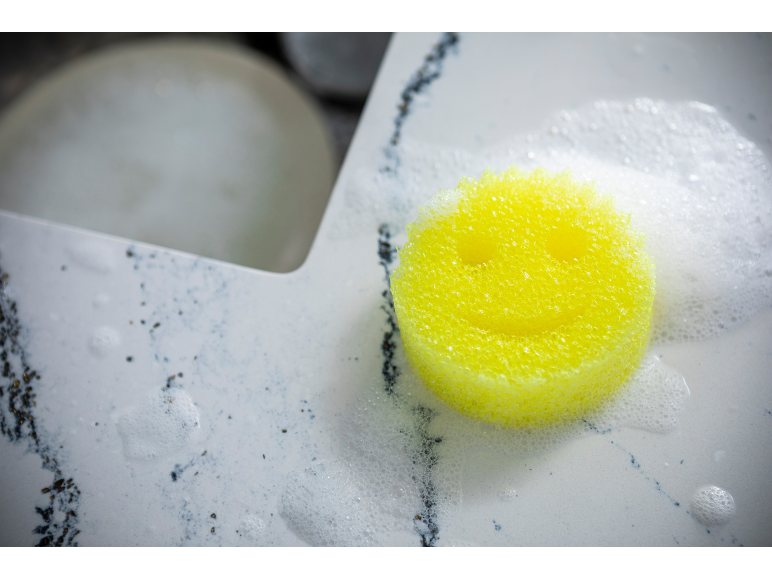 Éponge jaune souriante dans un évier moussant.