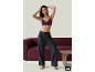 Femme en soutien-gorge violet et pantalon gris foncé devant un canapé