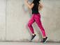 Une femme porte un legging rose et des baskets noires.