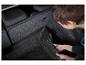 Une personne coupe un tapis de coffre en caoutchouc pour une voiture.