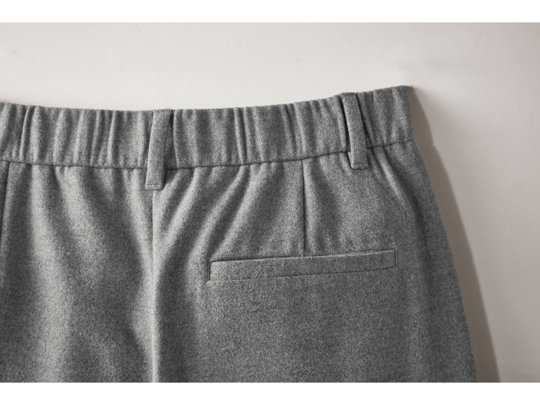 Gros plan sur la poche arrière et la taille élastique d'un pantalon gris.