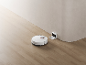 Aspirateur robot blanc avec sa station de charge sur un parquet.