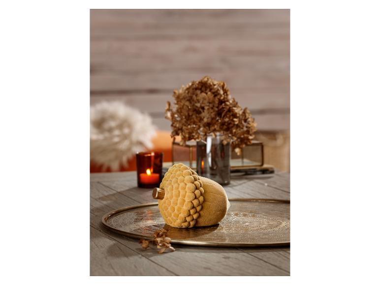 Objet décoratif en forme de gland avec finition en velours jaune sur un plateau métallique.