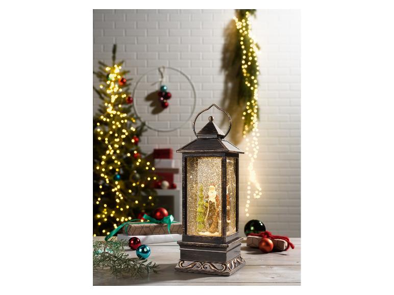 Lanterne de Noël avec le Père Noël et de la neige scintillante, entourée d'un sapin de Noël et de cadeaux.