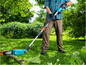 Un homme utilise une tronçonneuse électrique Gardena dans son jardin.