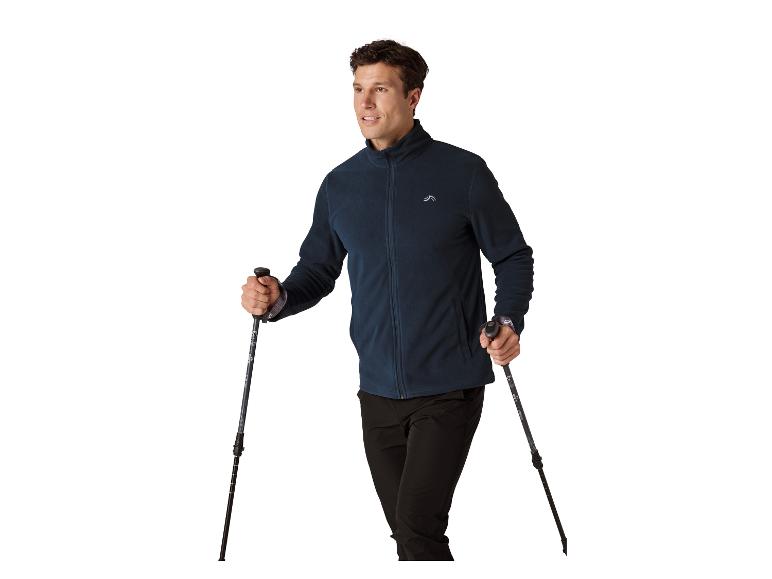 Homme en veste polaire bleue, tenant des bâtons de trekking.