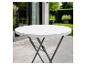 Table de jardin ronde blanche avec piètement métallique sur une terrasse verdoyante