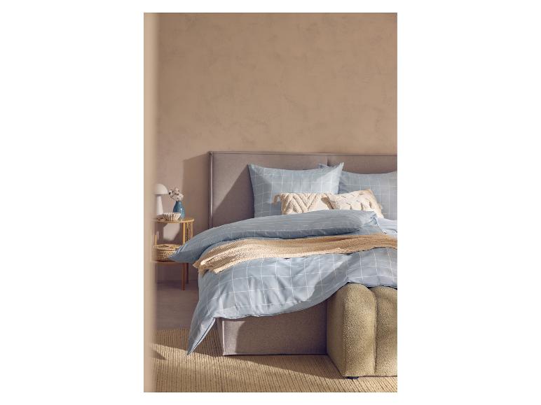 Lit avec parure de lit à carreaux bleus, jeté beige et table de chevet.