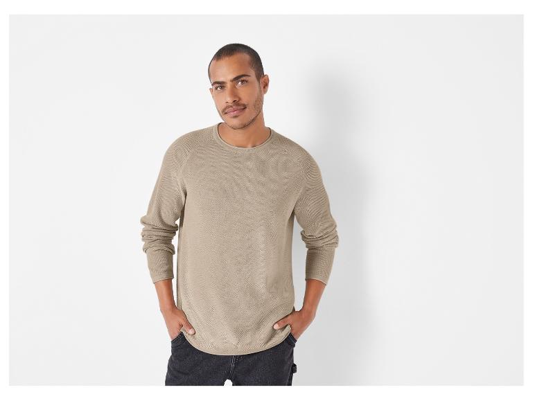 Un homme portant un pull en maille beige à manches longues.