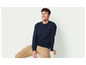 Un homme portant un pull bleu et un pantalon beige.