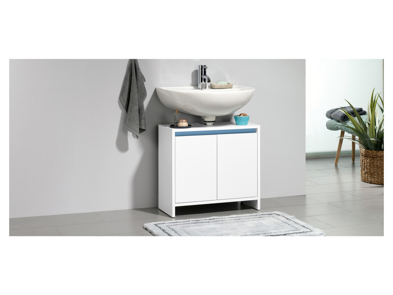 Un lavabo de salle de bain blanc avec une armoire en dessous et un tapis