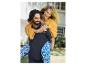 Couple heureux, vêtements décontractés : elle porte une robe orange, lui un polo noir et un pantalon bleu.