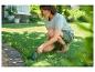 Femme coupant l'herbe le long d'un chemin avec un taille-herbe sans fil.