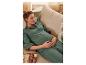 Maman enceinte relaxée en pyjama vert sur un canapé.