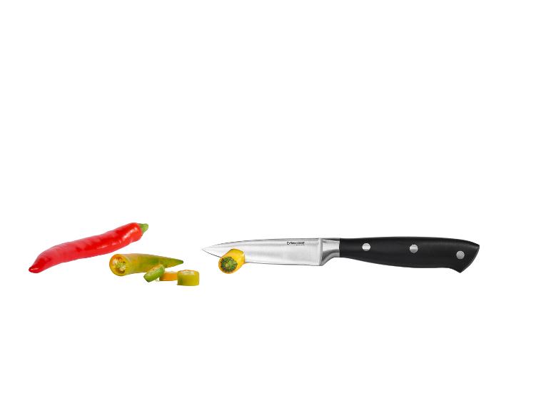 Couteau de cuisine avec des piments rouges et verts coupés sur fond blanc.