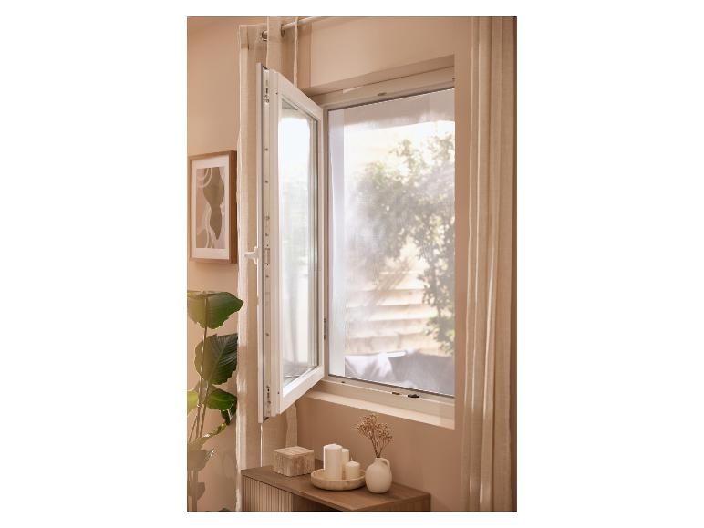 Fenêtre ouverte avec rideaux, plante et décorations sur une table d'appoint.