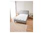 Un lit avec un matelas et un tapis beige dans une chambre à coucher.