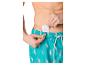 Un homme ajuste un short de bain turquoise à motif perroquet.