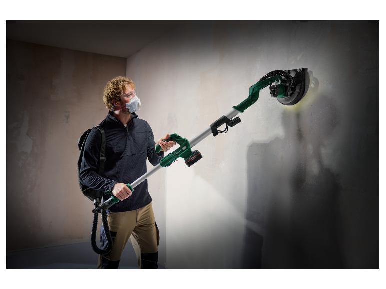 Un homme utilise une ponceuse Festool à long manche pour poncer un mur.