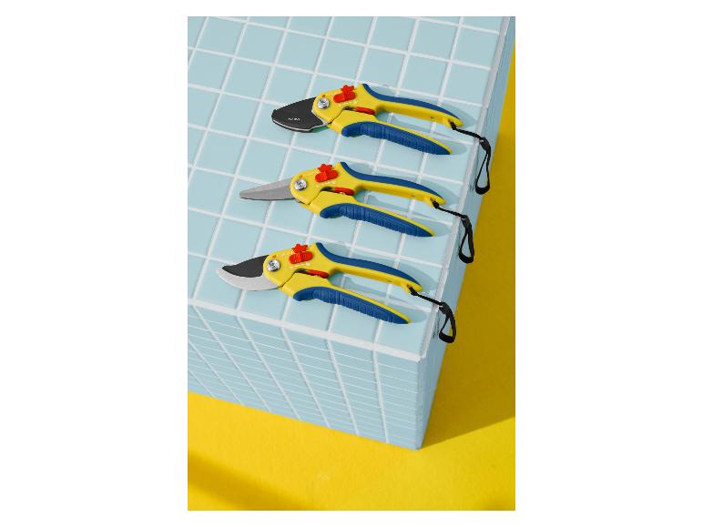 Trois sécateurs jaune et bleu, disposés sur un carreau bleu sur un fond jaune.