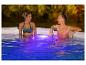 Deux femmes se détendent dans une piscine illuminée.