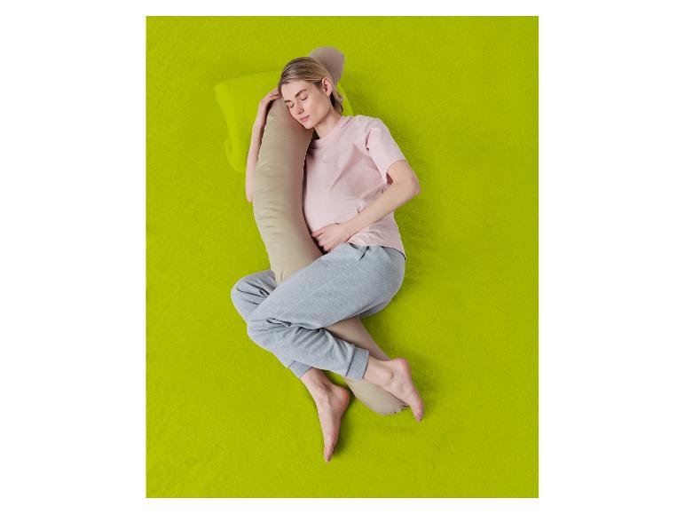 Femme dormant sur le côté avec un oreiller corporel sur fond vert.