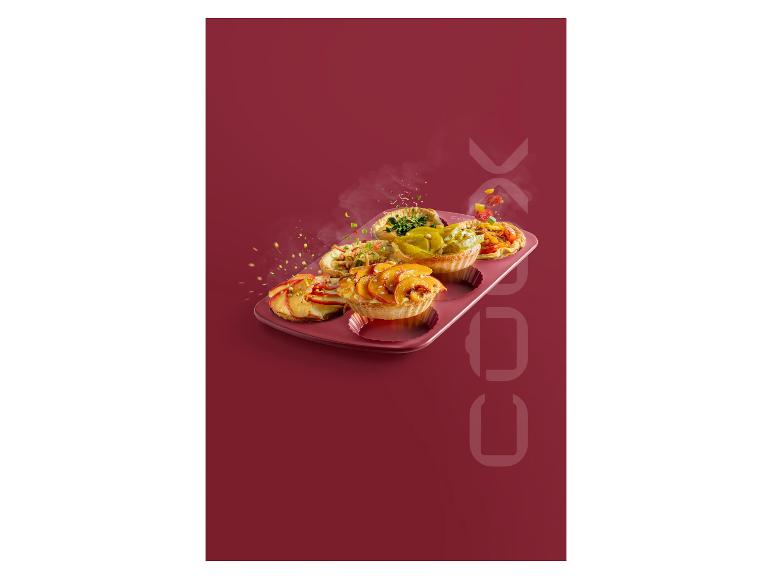 Quatre petites tartes dans un moule à pâtisserie sur un fond rouge.