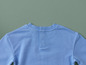 Un t-shirt bleu clair avec des boutons dans le dos.
