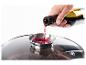 Vin rouge versé dans un couvercle de casserole en verre avec un entonnoir intégré.