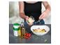 Femme saupoudrant du parmesan sur des pâtes aux tomates et basilic.