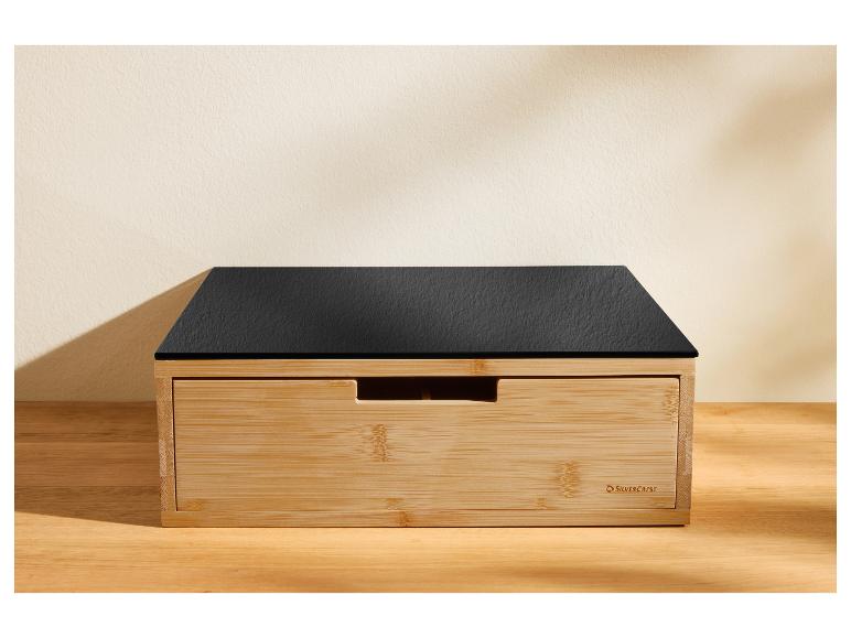 Une boîte à pain en bois avec un couvercle noir aspect ardoise sur une surface en bois.