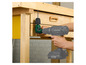 Une perceuse Parkside avec un adaptateur d'angle est utilisée pour percer une armoire en bois.