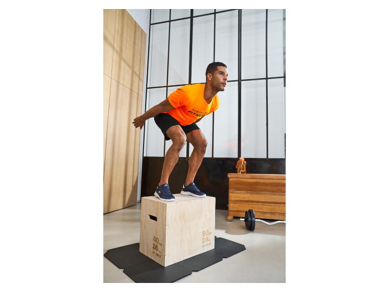 Homme en t-shirt orange et short noir s'entraînant avec une boîte en bois.